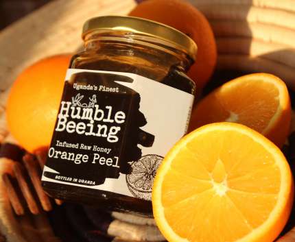 Humble Beeing orange peel infused raw honey jar beside fresh sliced oranges