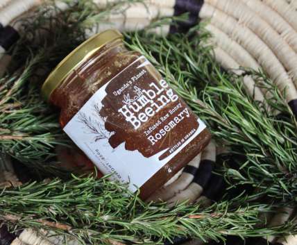 Humble Beeing rosemary infused raw honey jar resting on fresh rosemary sprigs