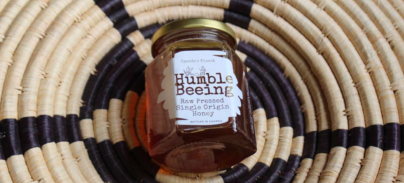 Jar of Humble Beeing raw pressed single-origin Yumbe shea blossom honey on a woven Ugandan basket